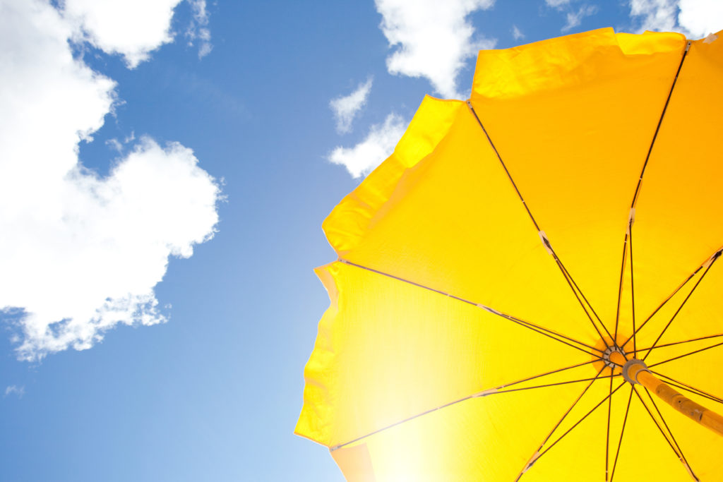 yellow umbrella on blue sky with clouds; 