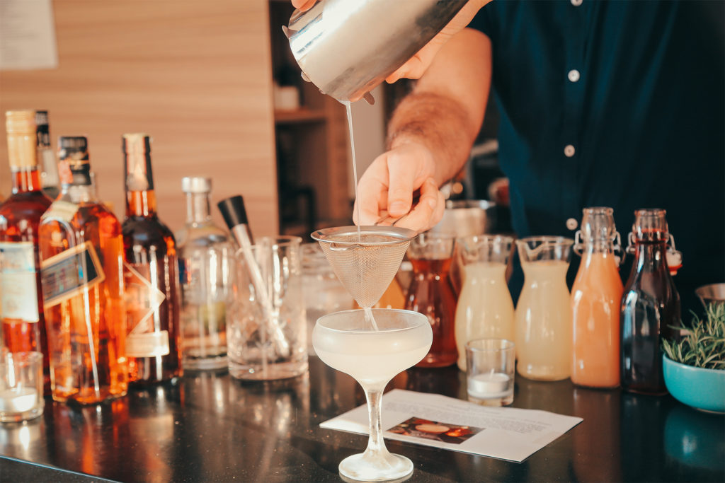 expert bartender is making a cocktail at home party.
