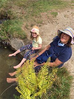 Woman and child dangling feet in pond