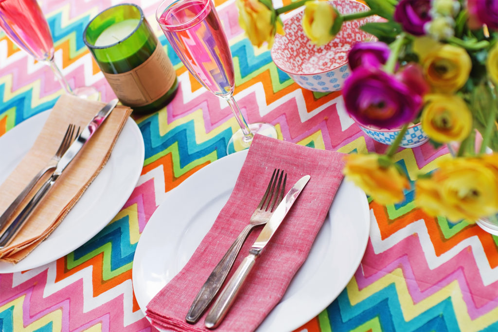 Bright colorful table setting with multi-colored chevron pattern tablecloth; outdoor table settings