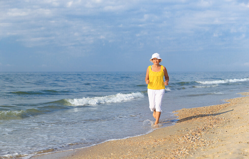 senior woman jogging on sea beach at the morning;