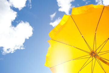 yellow umbrella on blue sky with clouds;