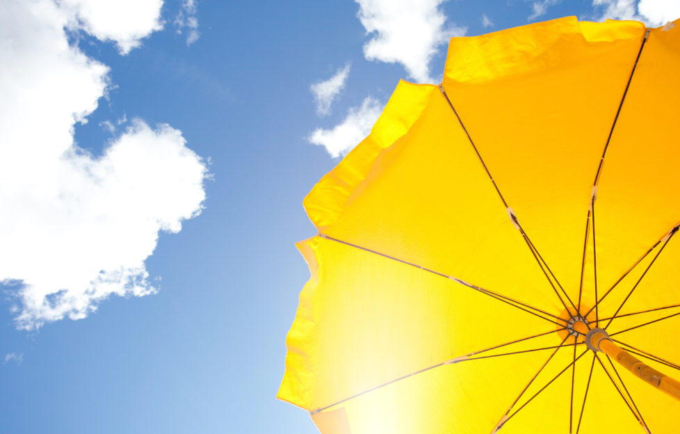 yellow umbrella on blue sky with clouds;