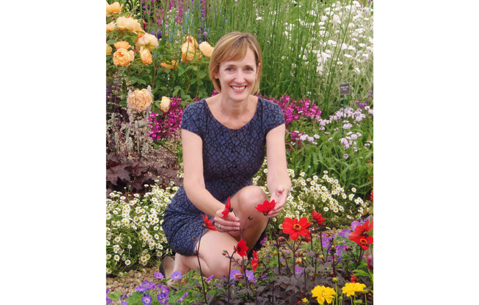Sarah Squire, chair of Squires garden centres, kneeling amid colourful mixed flower border