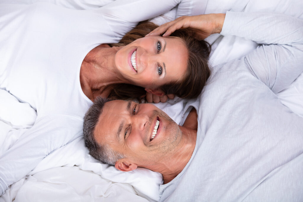 High Angle View Of Happy Mature Couple Lying On Bed; 