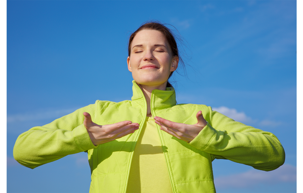 Brunette in lime green jacket doing breathing exercises outdoors