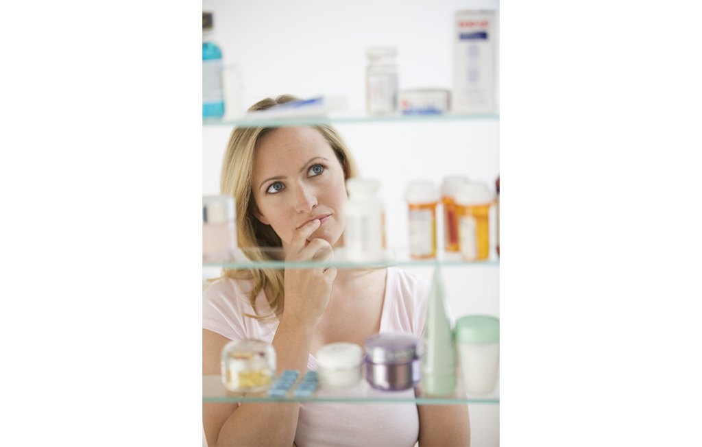 Blonde woman looking in medicine cabinet in bathroom