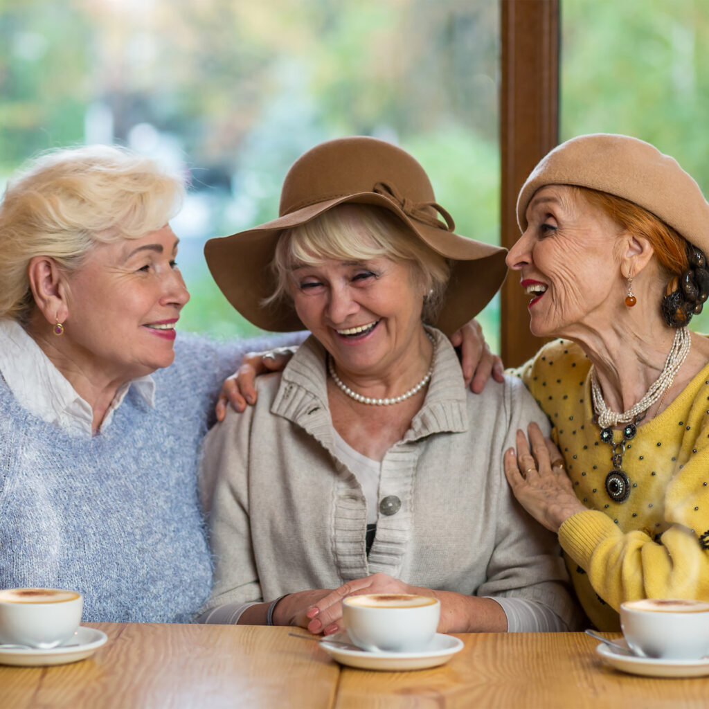 Senior women laughing at table. Happy ladies in cafe.