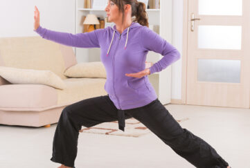 Beautiful woman doing qi gong tai chi exercise at home;