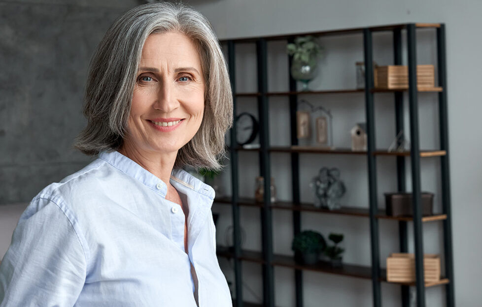 Smiling confident stylish mature middle aged woman standing at home office. Old senior businesswoman, 60s grey-haired elegant lady executive business leader manager looking at camera,