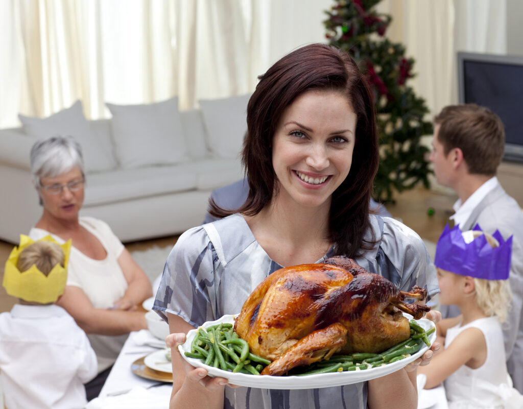 Woman showing Christmas turkey for family dinner at home; 
