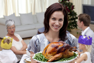 Woman showing Christmas turkey for family dinner at home;