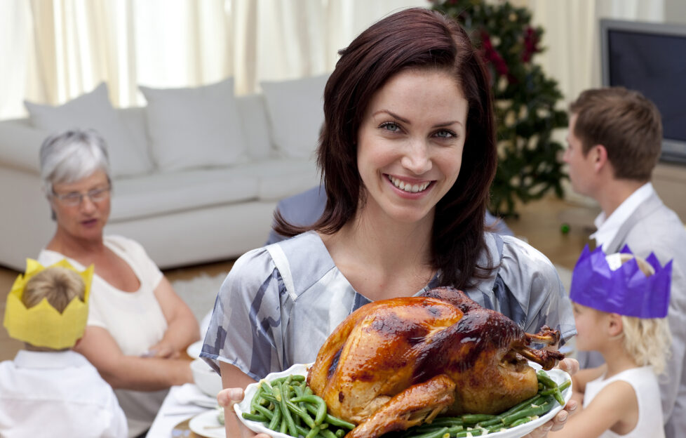 Woman showing Christmas turkey for family dinner at home;