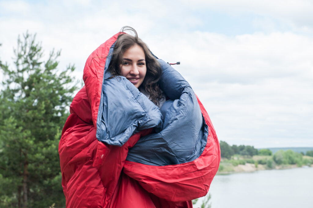 pretty girl tourist with red sleeping bag outdoor; 