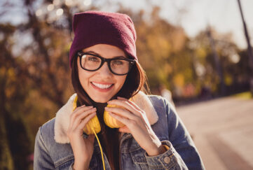 Dark haired woman with glasses who has headphones round her neck out for a walk