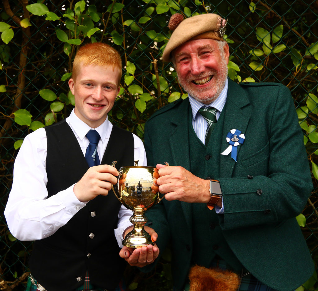 Ross Conner, Campbeltown, is presented with the trophy for intermediate march, strathspey and reel by Torquil Telfer, piping steward.