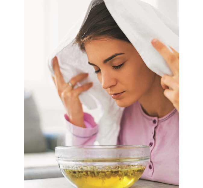 woman with cold holding head over bowl