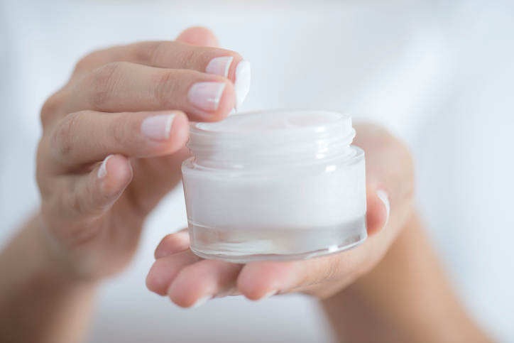 Female hand holding moisturizer in hand, horiztonal. moisturisers