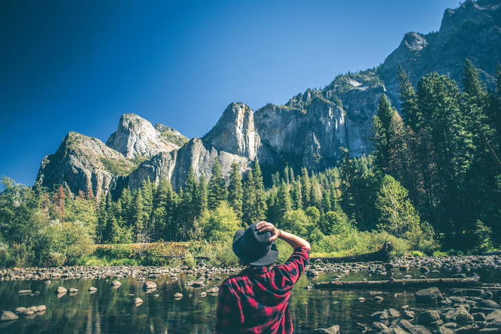 A shot of a young woman walking along a river in a majestic landscape. lift your mood