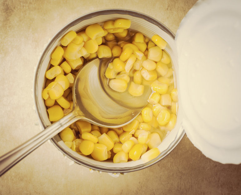 Sweet corn in an open tin can with a spoon. Top view. good food