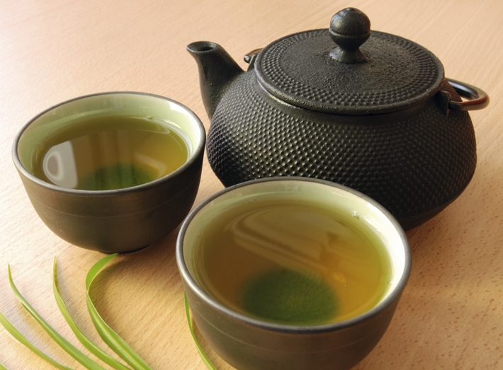 Cast iron teapot with two cups of green tea.