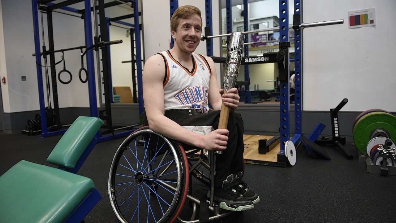 James MacSorley representing Northern Ireland at Wheelchair Basketball holds the Commonwealth Games Baton