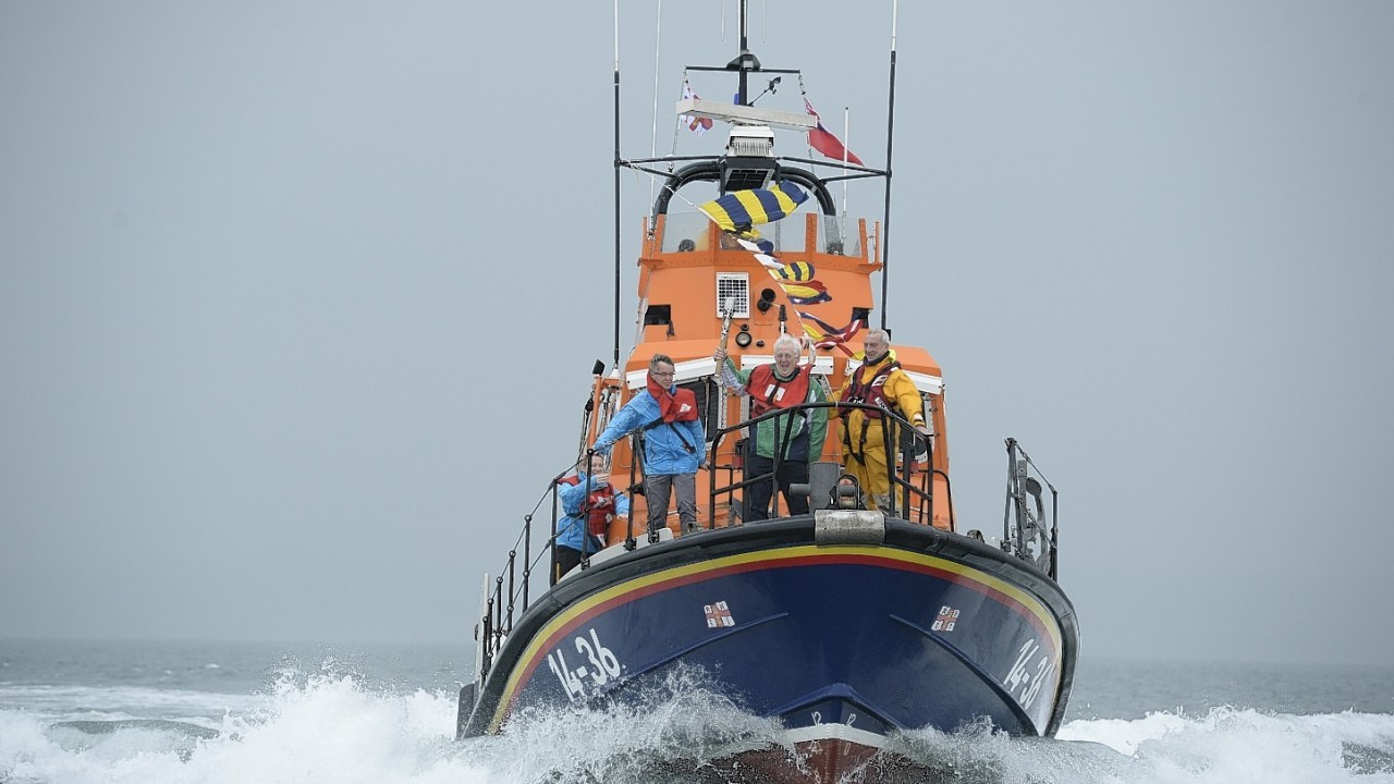 Robert McVeigh holds the Commonwealth Games Baton aboard an RNLI RIB off the coast of Northern Ireland