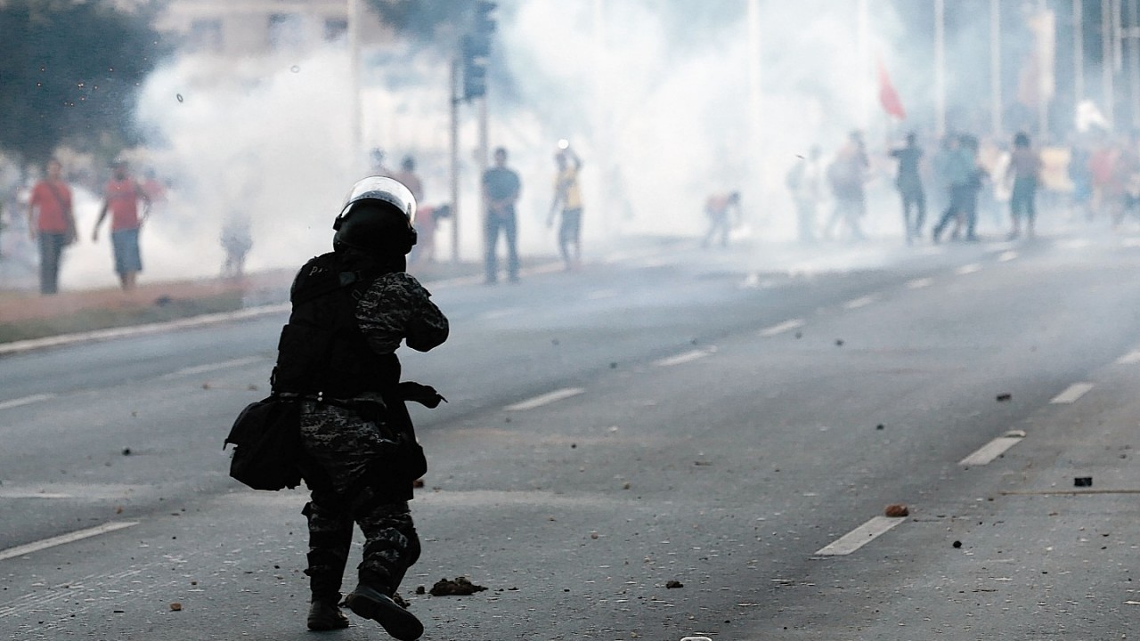 A military police officer fires a tear gas grenade against demonstrators during a protest against the FIFA World Cup outside the National Stadium in Brasilia, Brazil,