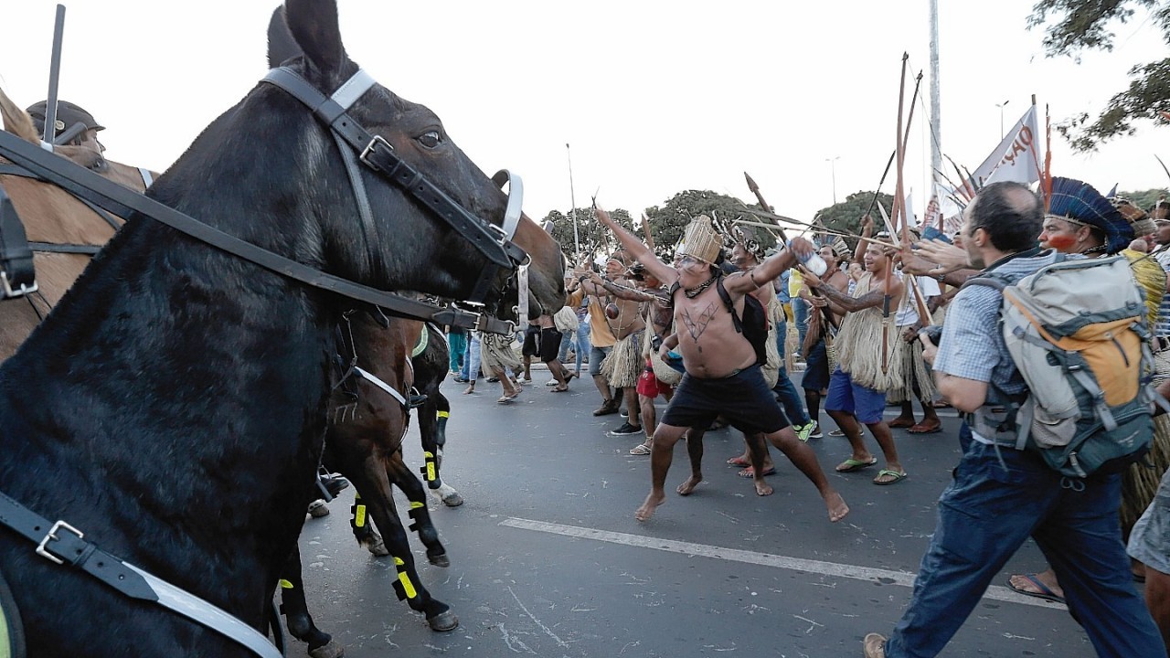 Indigenous protesters in traditional headdress clash with military police during a protest against FIFA World Cup outside the National Stadium in Brasilia, Brazil