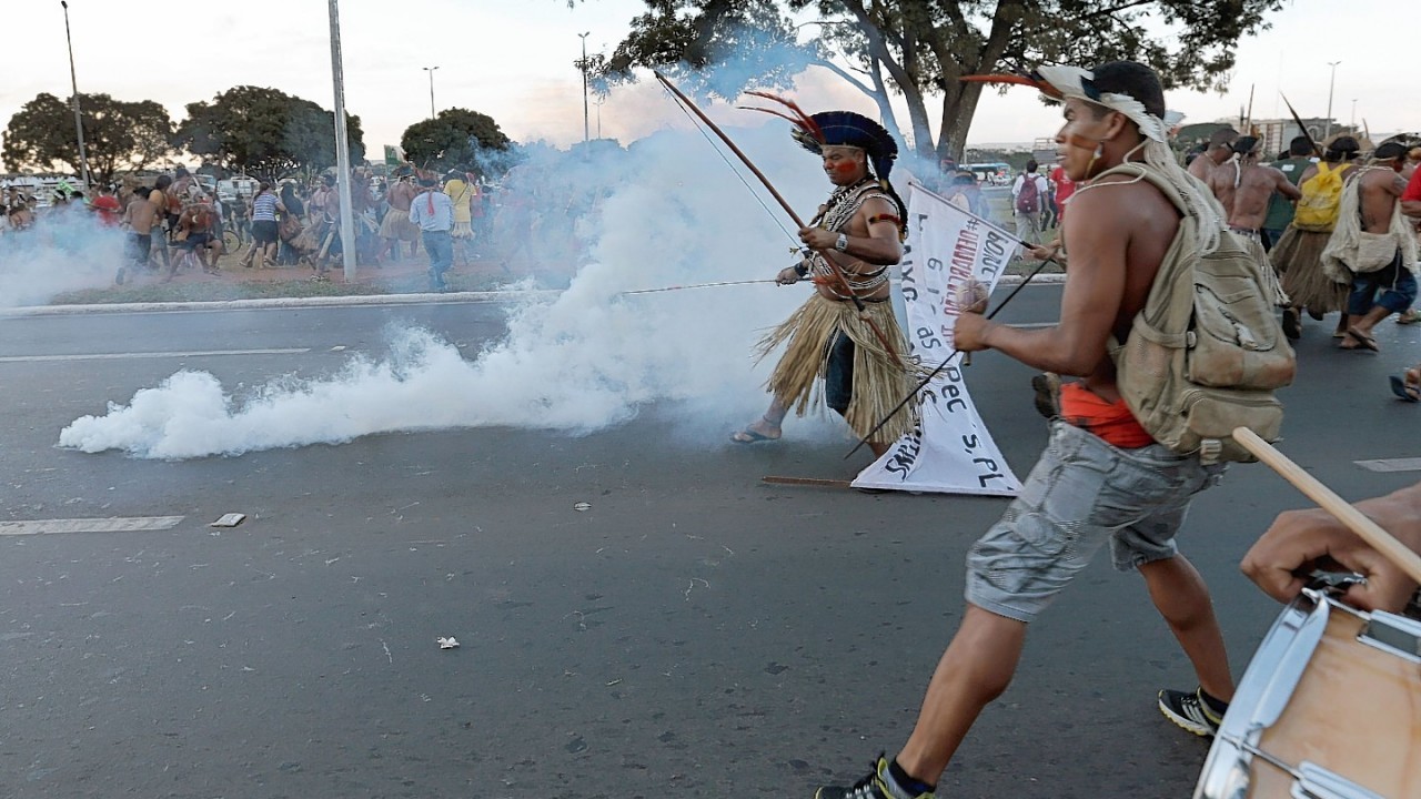 Indigenous protesters in traditional headdress clash with military police during a protest against the FIFA World Cup outside the National Stadium in Brasilia, Brazil