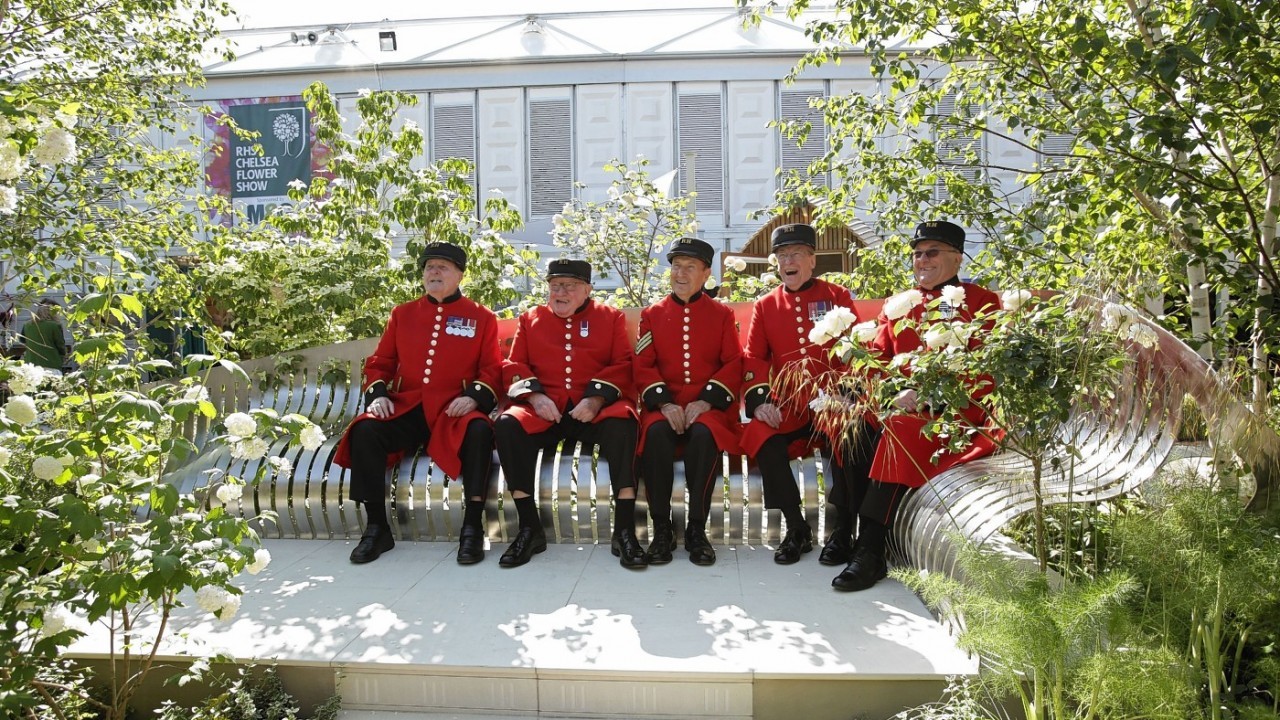 Five Chelsea Pensioners enjoy a quiet moment on a bench in a London garden square, designed by gold medal winner Jo Thompson