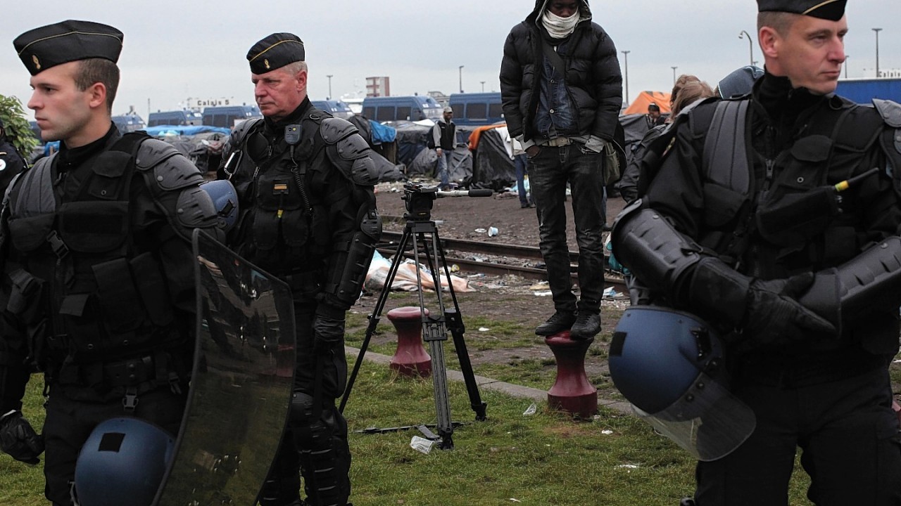 Police officers take positions in a makeshift camp housing hundreds of illegal migrants from Syria, Afghanistan and Africa, after French authorities started to clear out camps in the English Channel port city of Calais, northern France, Wednesday, May 28, 2014. French media reports say that Calais authorities wanted the camps cleared out because of a scabies epidemic.