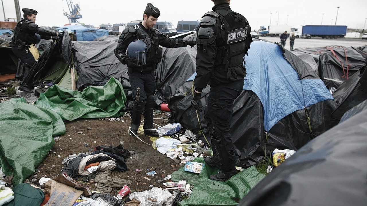 Police officers take positions in a makeshift camp housing hundreds of illegal migrants from Syria, Afghanistan and Africa, after French authorities started to clear out camps in the English Channel port city of Calais, northern France, Wednesday, May 28, 2014. French media reports say that Calais authorities wanted the camps cleared out because of a scabies epidemic.