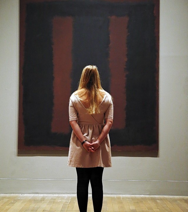 A Tate Modern employee poses for the photographers in front of Mark Rothko’s mural ‘Black on Maroon’, in London
