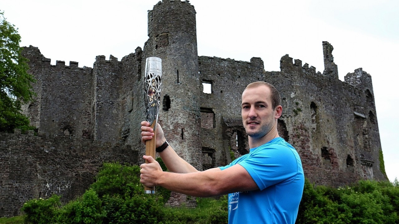 Queen's Baton relay of Baton Bearer Lee Williams holding the Queen's Baton Laugharne Castle in Wales. Wales is nation 68 of 70 nations and territories the Queen's Baton will visit