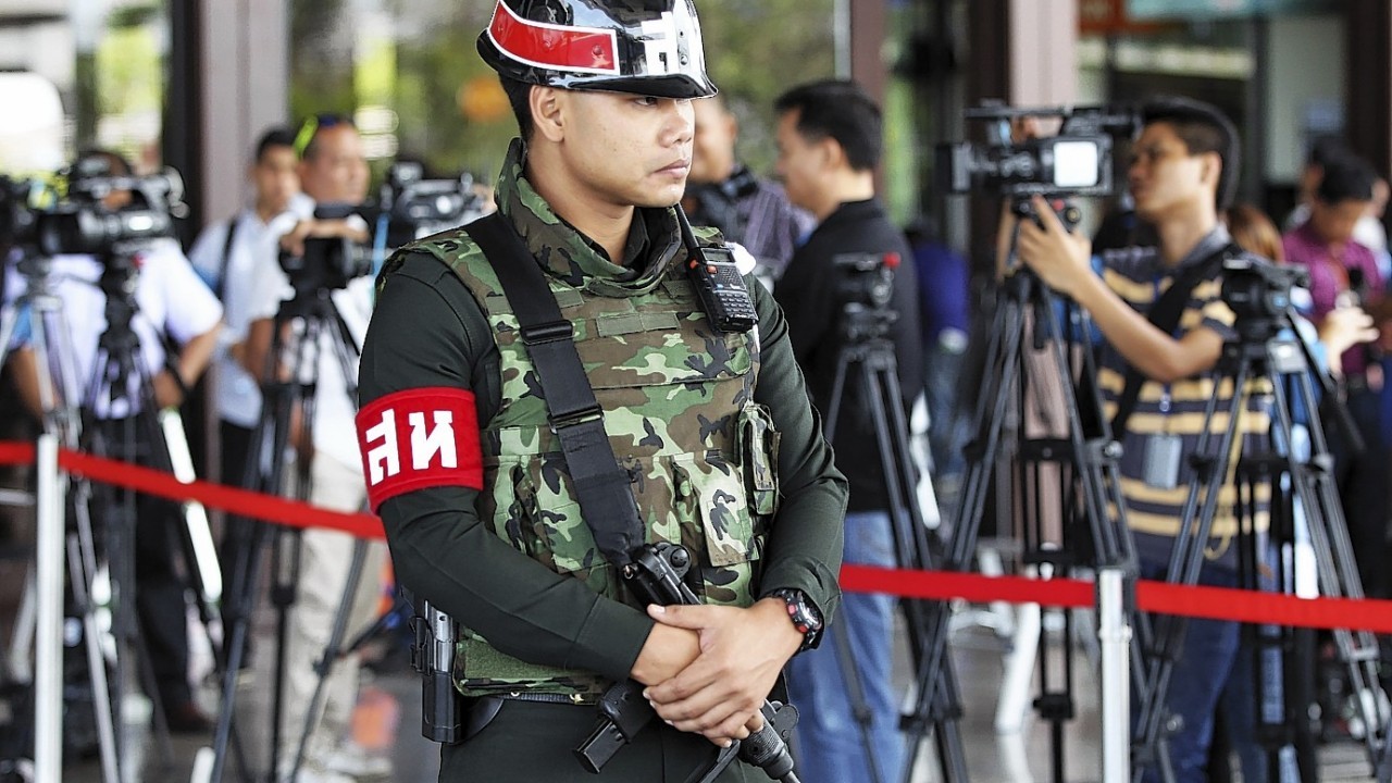 An armed Thai military police stands guard at the entrance to a hall of the army club prior to a meeting between Thai Armed Forces Chiefs and high ranking officials Tuesday, May 20, 2014 in Bangkok