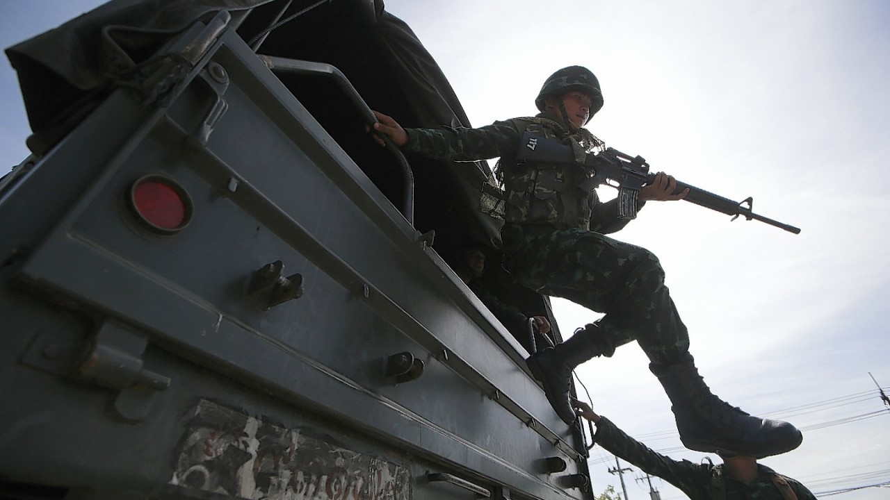 A Thai soldier jumps off a military truck after arriving at a pro-government rally site on the outskirts of Bangkok, Thailand