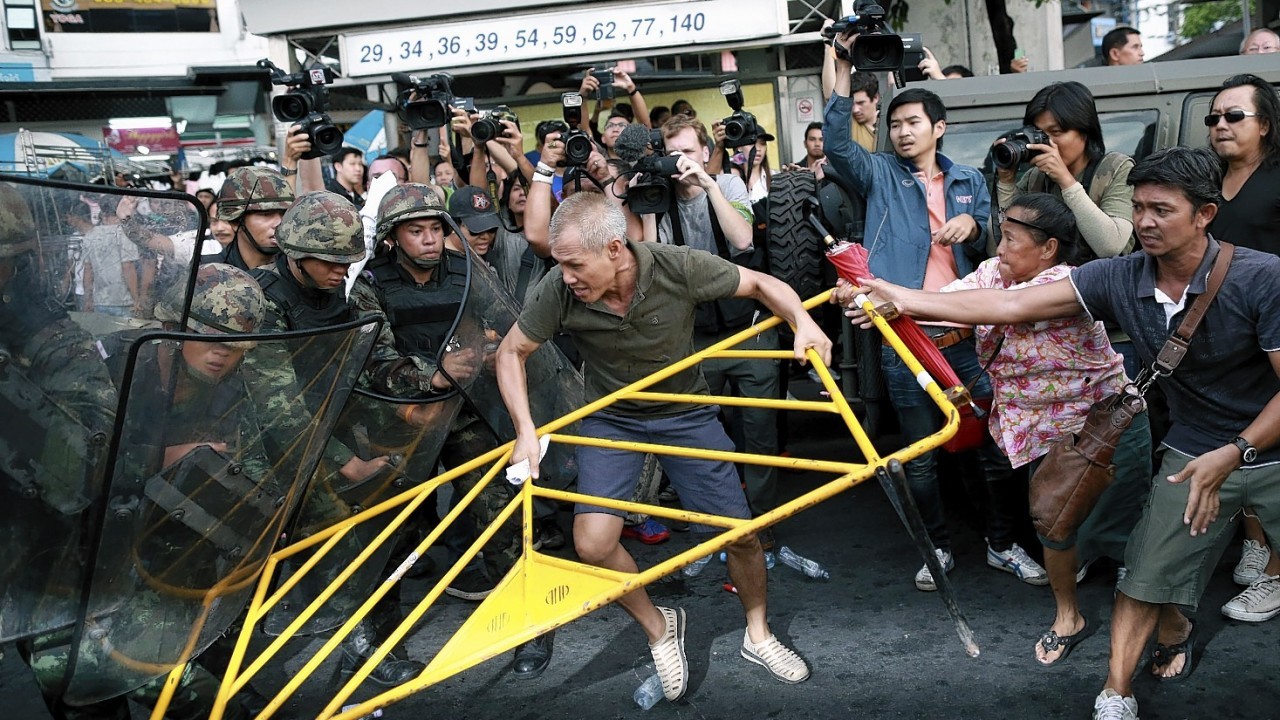 Protesters scuffle with Thai soldiers during an anti-coup demonstration at the Victory Monument in Bangkok, Thailand Wednesday, May 28, 2014. Thailand's new military junta aired videos Wednesday on television stations nationwide showing some of the prominent political figures it has detained as part of an effort to convince the public that detainees in army custody are being treated well.