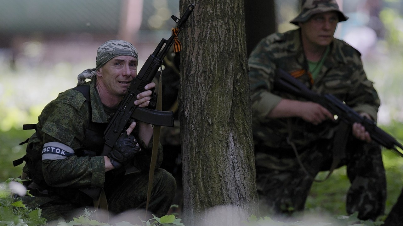 A pro-Russian gunman takes cover behind a tree during shooting near the airport, outside Donetsk, Ukraine