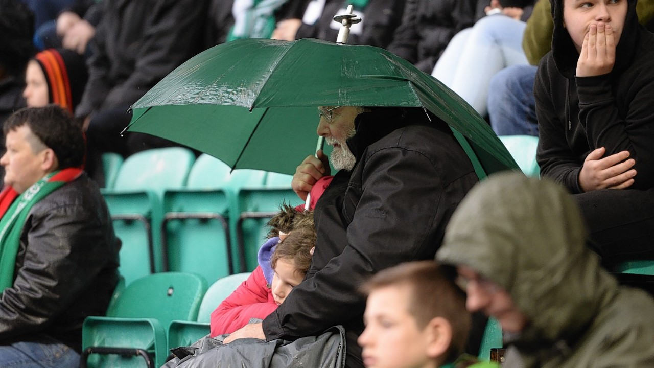 A Hibernian supporter gains some extra shelter from an umbrella.
