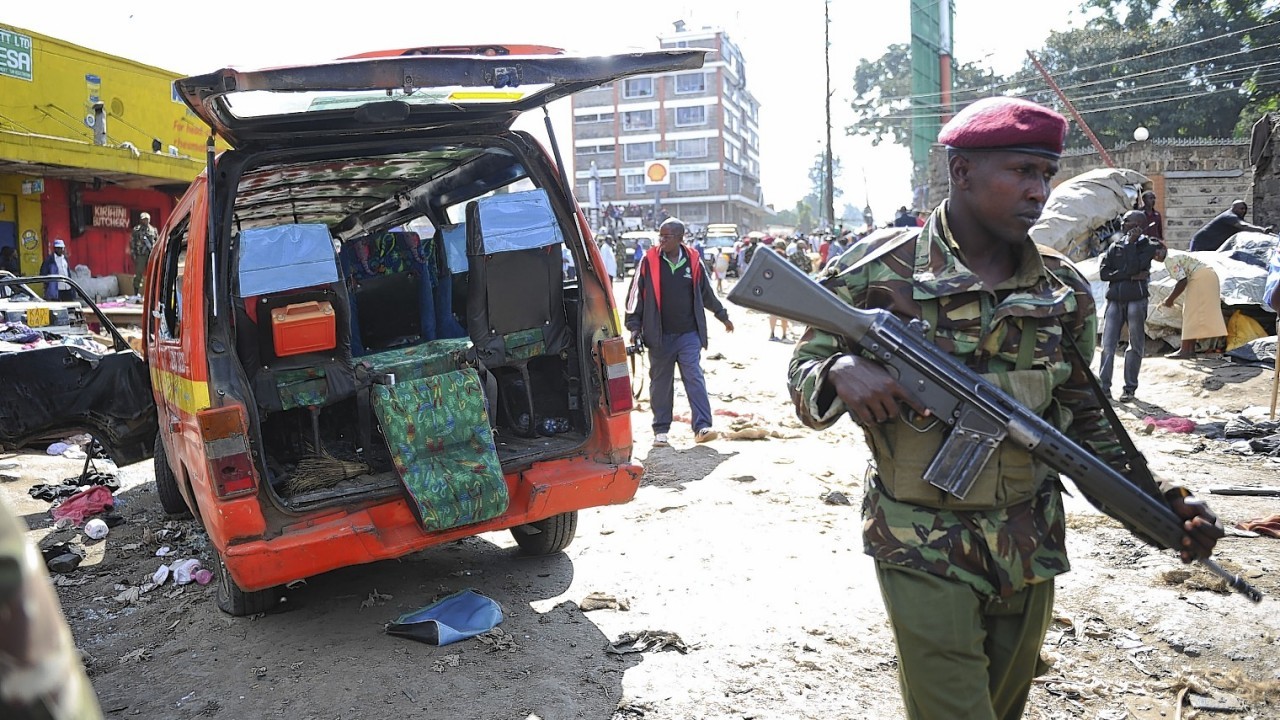 A member of the security forces patrols at the site where two blasts detonated, one in a mini-van used for public transportation, in a market area of Nairobi, Kenya