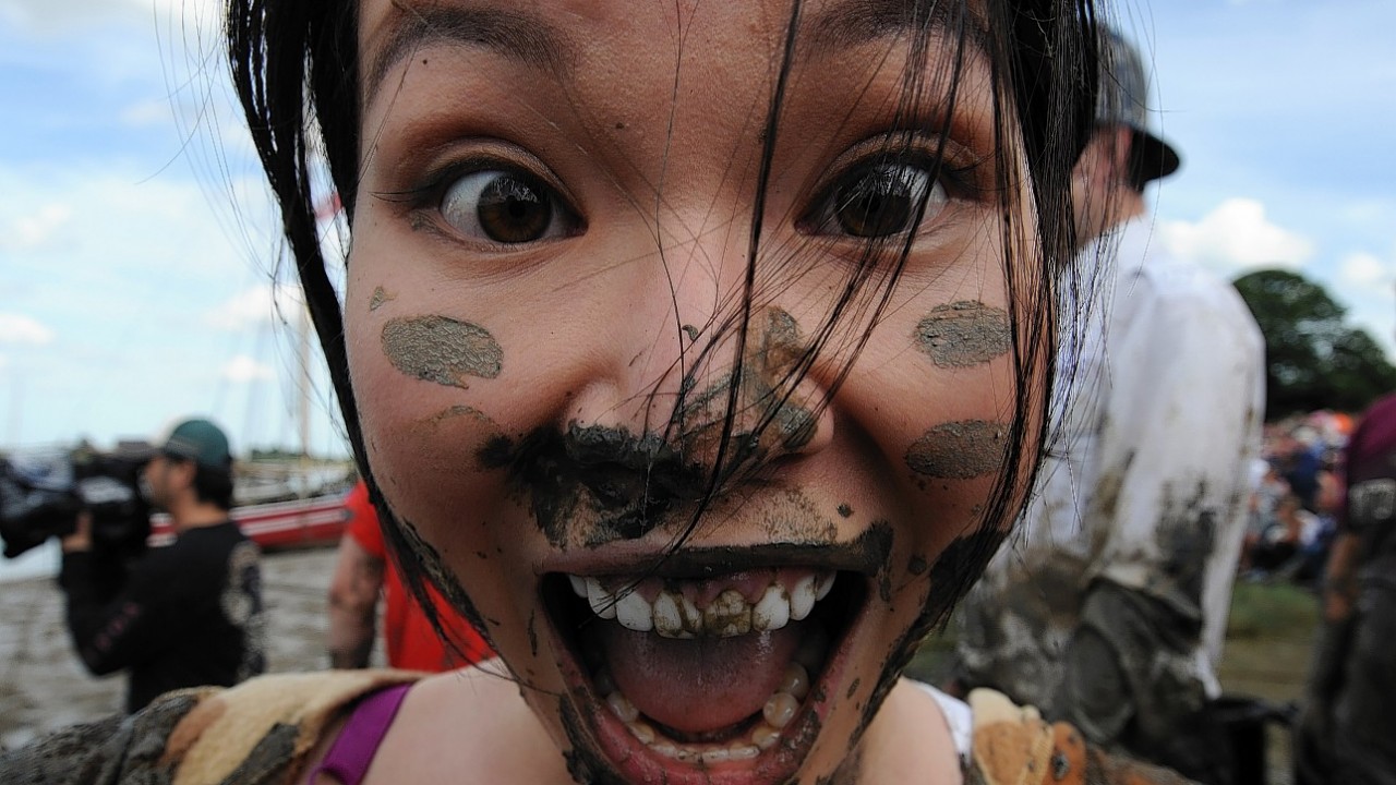 A competitor smiles after taking part in the Maldon Mud Race, a charity event on the River Blackwater in Maldon, Essex