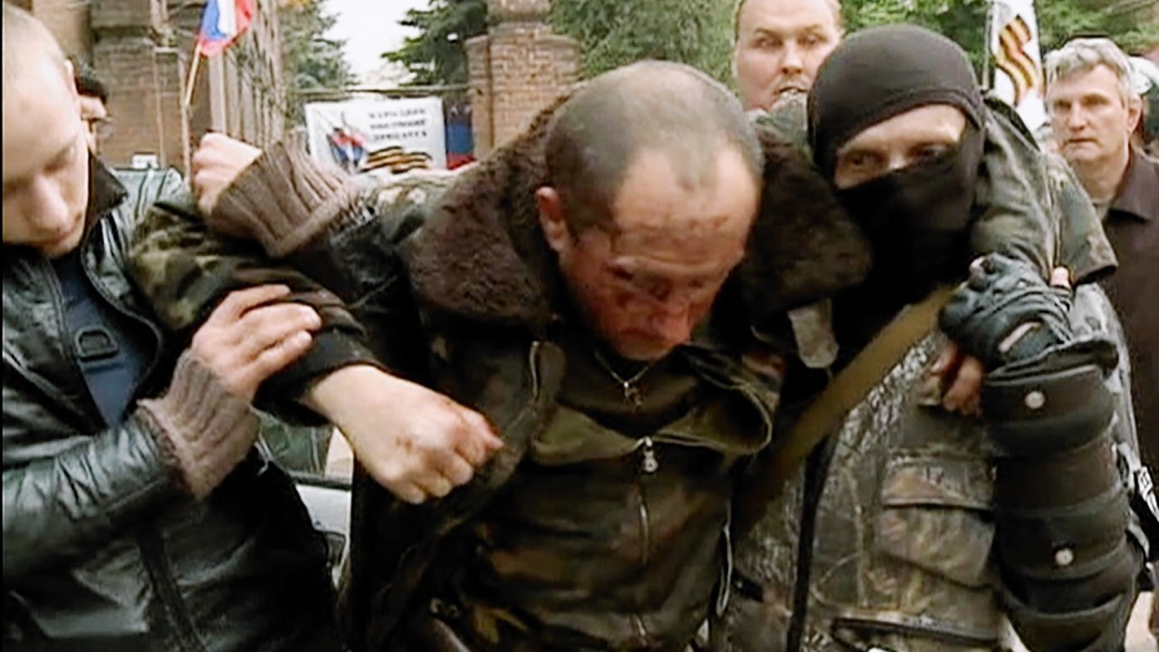 In this image taken from Rossia 24 television channel TV, an injured Ukrainian military helicopter pilot is assisted by pro-Russian activists after he was shot down in Slovyansk, eastern Ukraine.