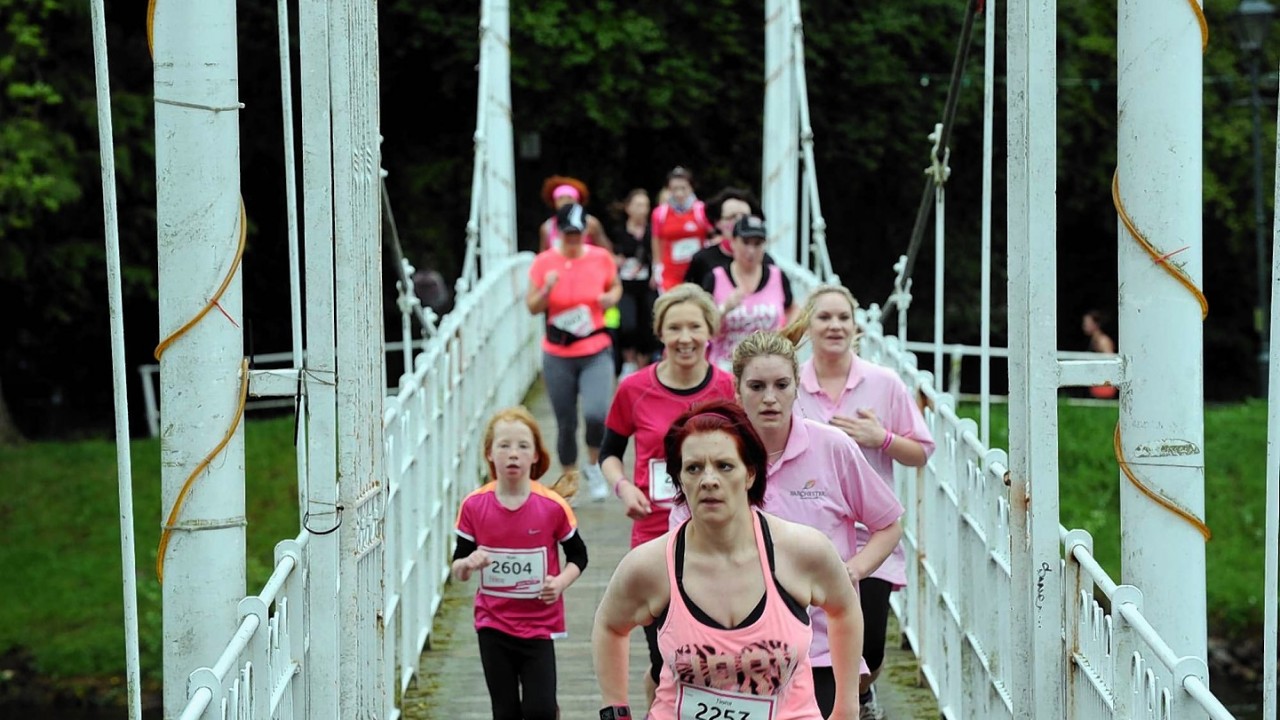 Race For Life at the Bught Park, Inverness. Runners crossing a suspension bridge at Ness islands on their way to the finish.
