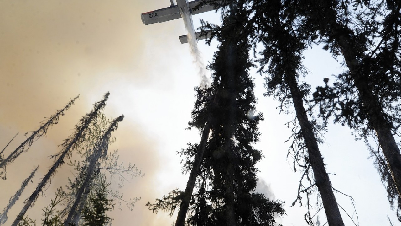 A plane sprays over a portion of a wildfire Sunday, May 25, 2014, in the Funny River community of Soldotna, Alaska. A massive wildfire pushed by wind in Alaska's Kenai Peninsula south of Anchorage continued to explode in size, leading to mandatory evacuations of 1,000 structures,