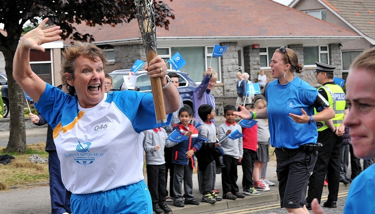 A batonbearer is cheered on by pupils from Fernielea Primary as she makes her way along the Kings Gate, Aberdeen.