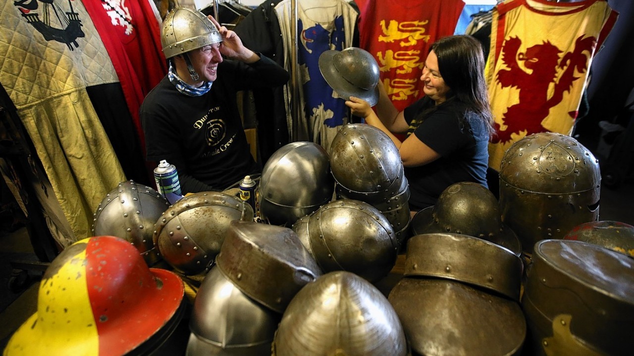Annette Grier with Keith Bremner  from the Clanranald Trust                     as he tries on a helmet as she lines, polishes and fixes straps to helmets along with making adjustments to costumes during final preparations for the Battle of Bannockburn performance being held at Bannockburn Live Event in Bannockburn on the 28th and 29th June as the Battle of Bannockburn's 700th anniversary is celebrated