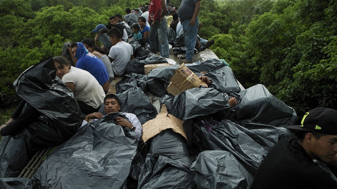 Central American migrants use trash bags and cardboard to protect themselves from the rain as they wait atop a stuck freight train, outside Reforma de Pineda, Chiapas state, Mexico.