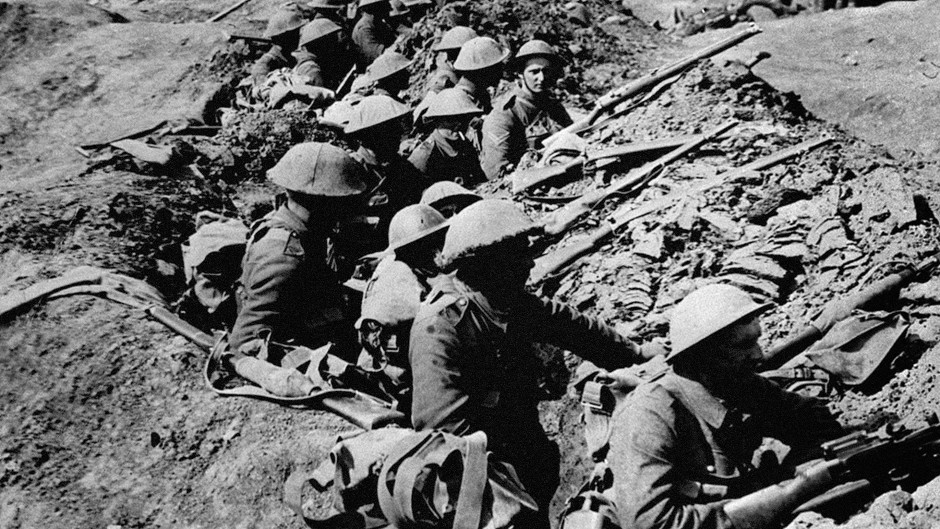 British infantrymen occupy a shallow trench in a ruined landscape before an advance during the Battle of the Somme