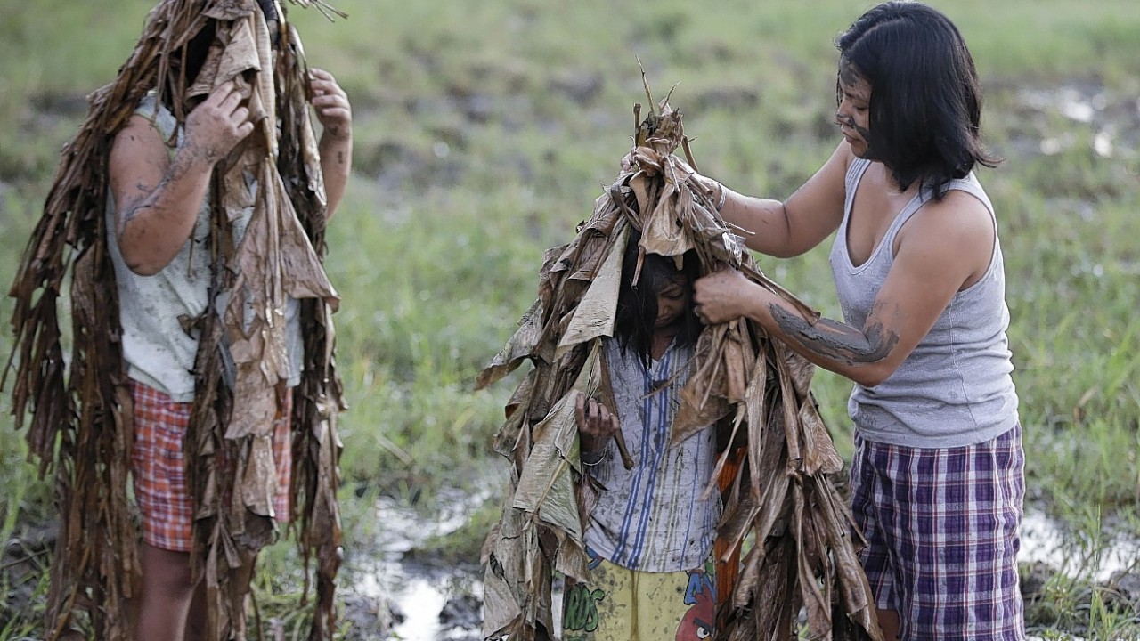 Residents don dried Banana leaves after applying mud on their bodies prior to attending a mass to celebrate the Feast Day of St. John the Baptist at the village of Bibiclat, Aliaga township, Nueva Ecija province in northern Philippines